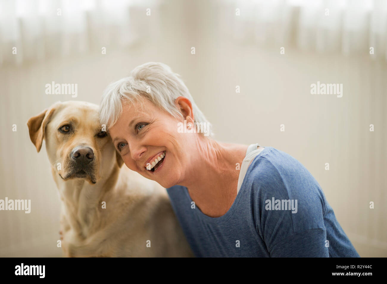 Felice donna matura avvolge il suo Golden Labrador. Foto Stock