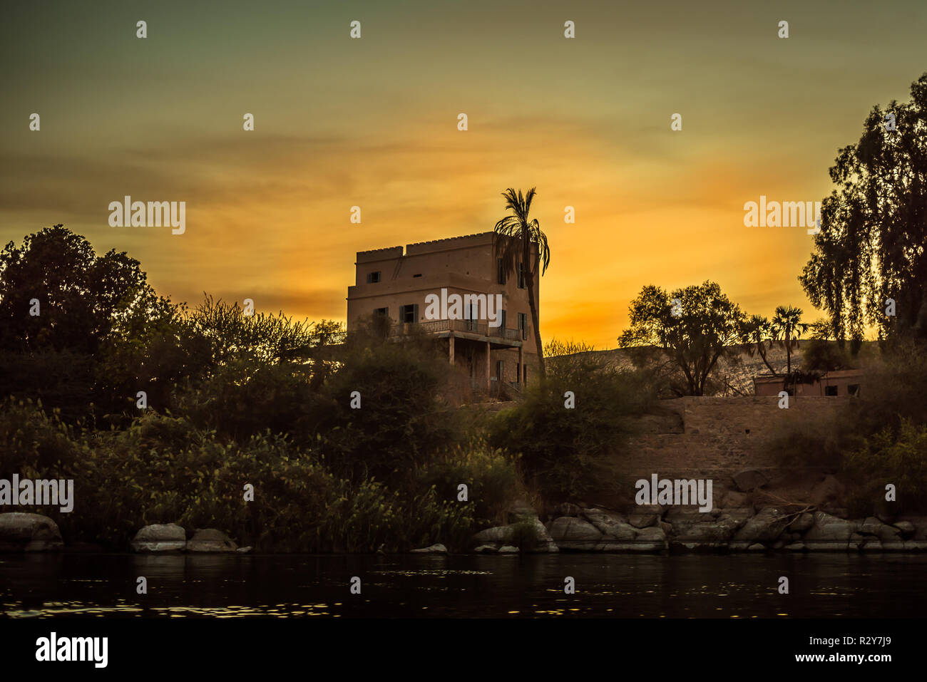 Scenic tramonto sulle rive del fiume Nilo. Un castello e di palme contro il cielo rosso. Nilo, Egitto, 26 Ottobre 2018 Foto Stock
