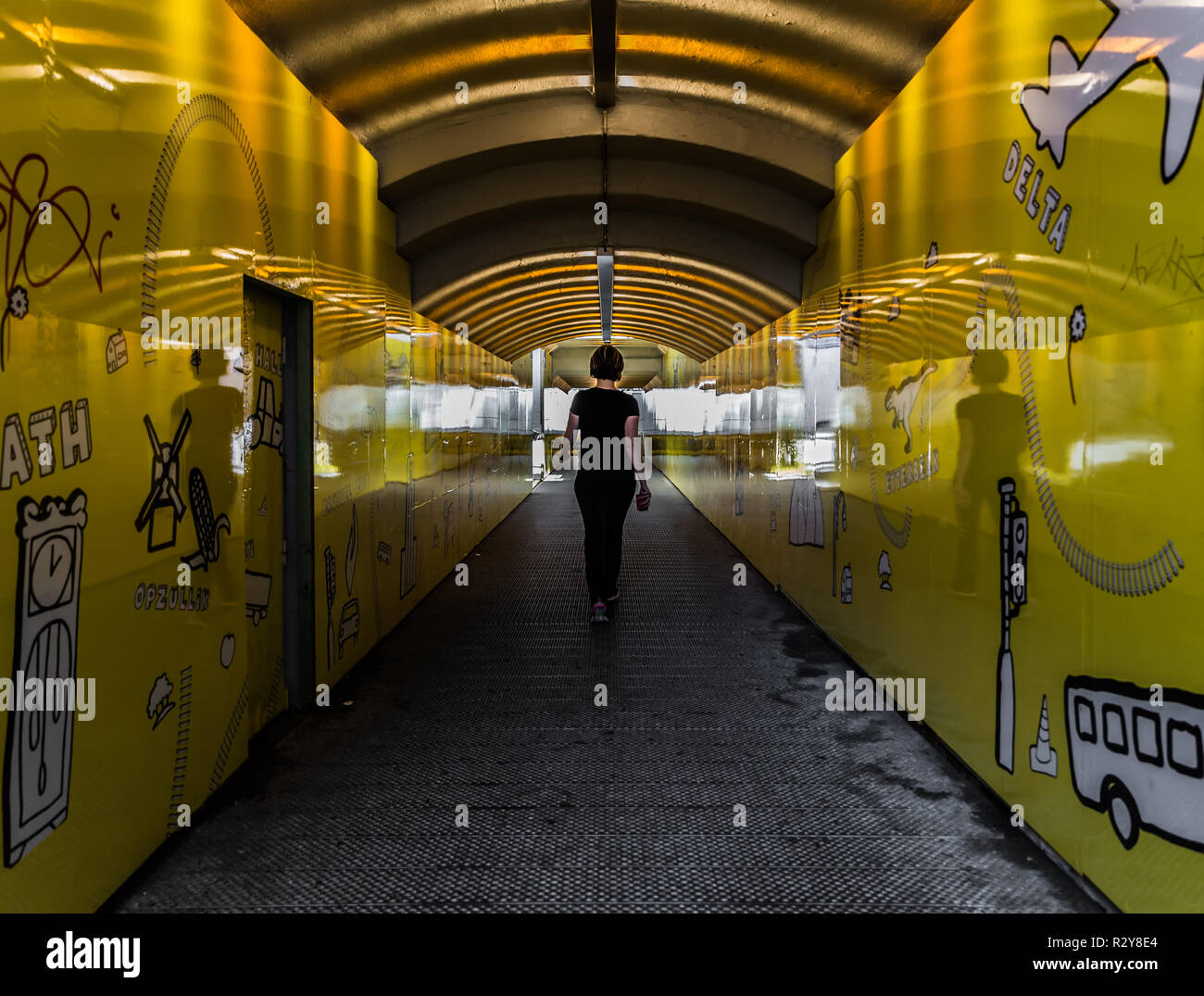 Giovane donna sportivo a piedi attraverso un giallo tunnel pedestrain Foto Stock