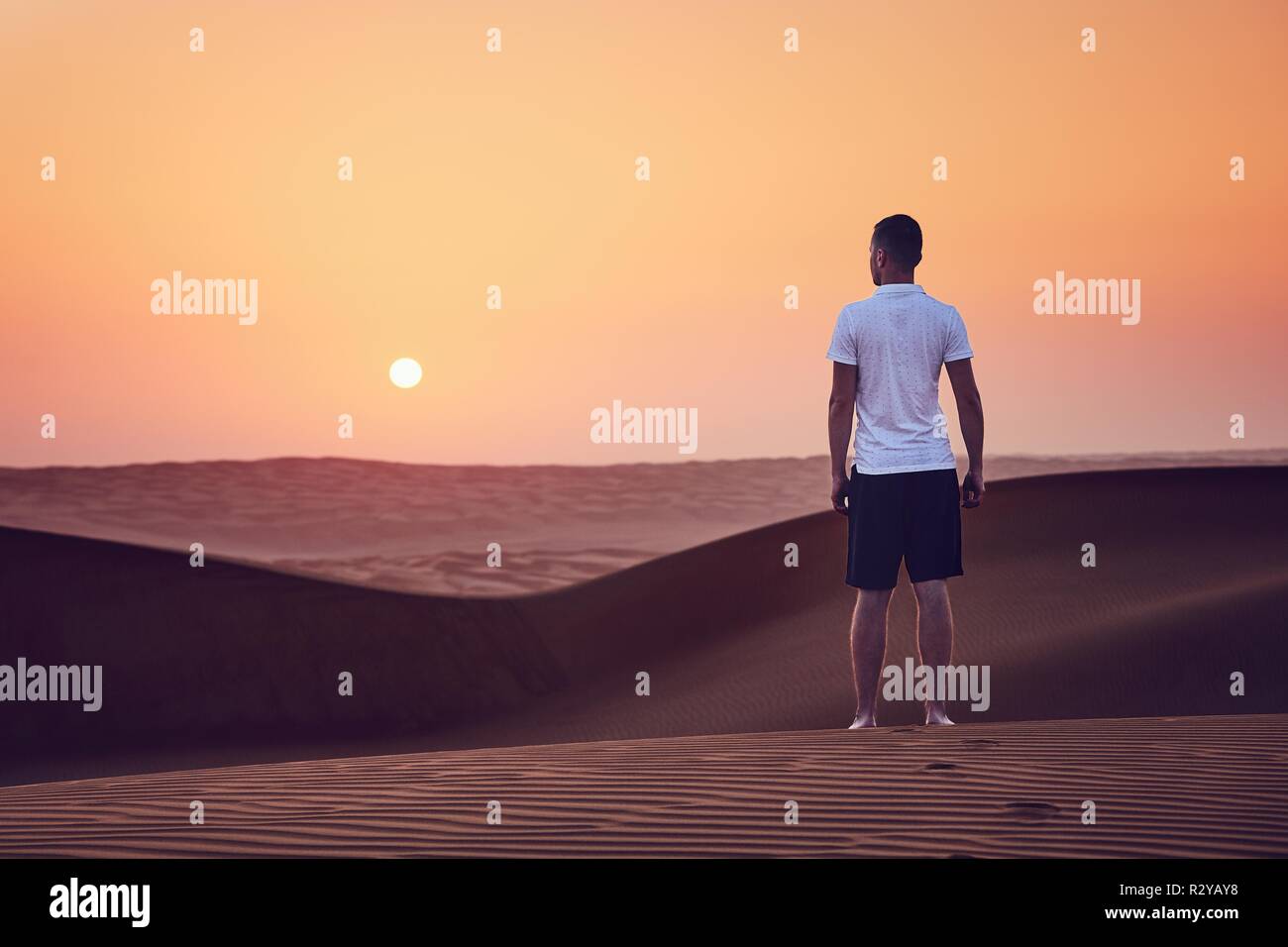 Sunrise nel deserto. Lonely Man camminando sulle dune di sabbia. Wahiba Sands in Oman. Foto Stock
