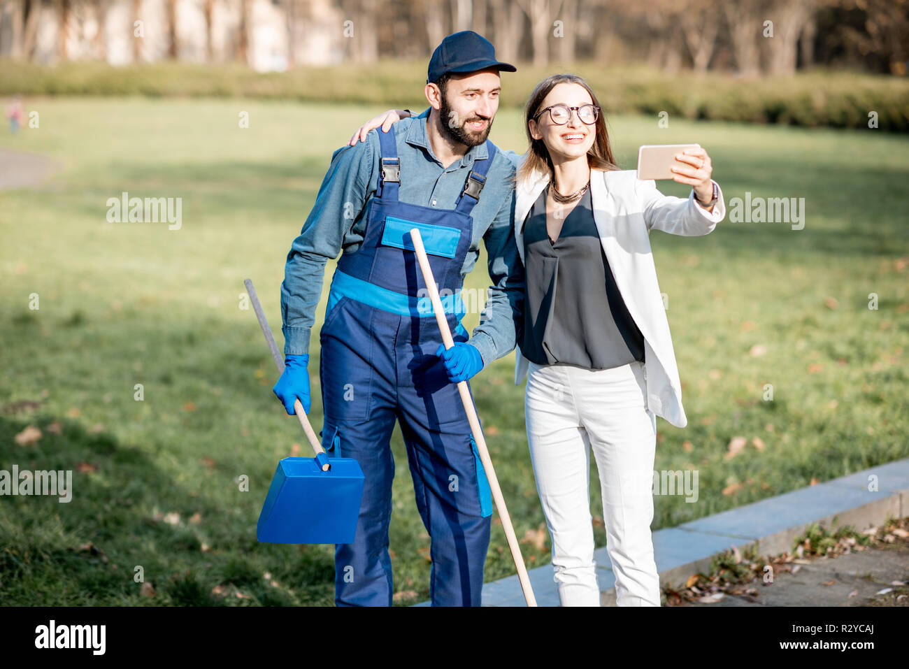 Imprenditrice e spazzatrice rendendo selfie foto insieme all'esterno. Povertà e ricchezza concept Foto Stock