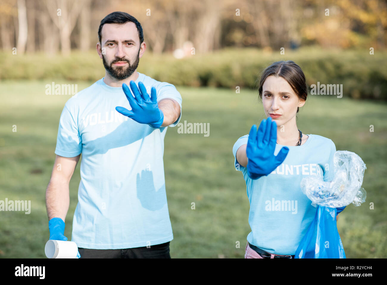 Ritratto di un uomo e di una donna i volontari in blu t-shirt con sacchi per immondizia che mostra fermo con le mani preoccupati per l'ambiente Foto Stock