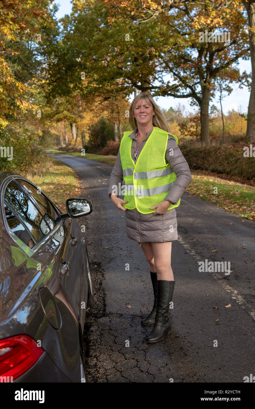 Donna automobilista dalla sua auto mettendo su una riflettente giubbotto di sicurezza Foto Stock