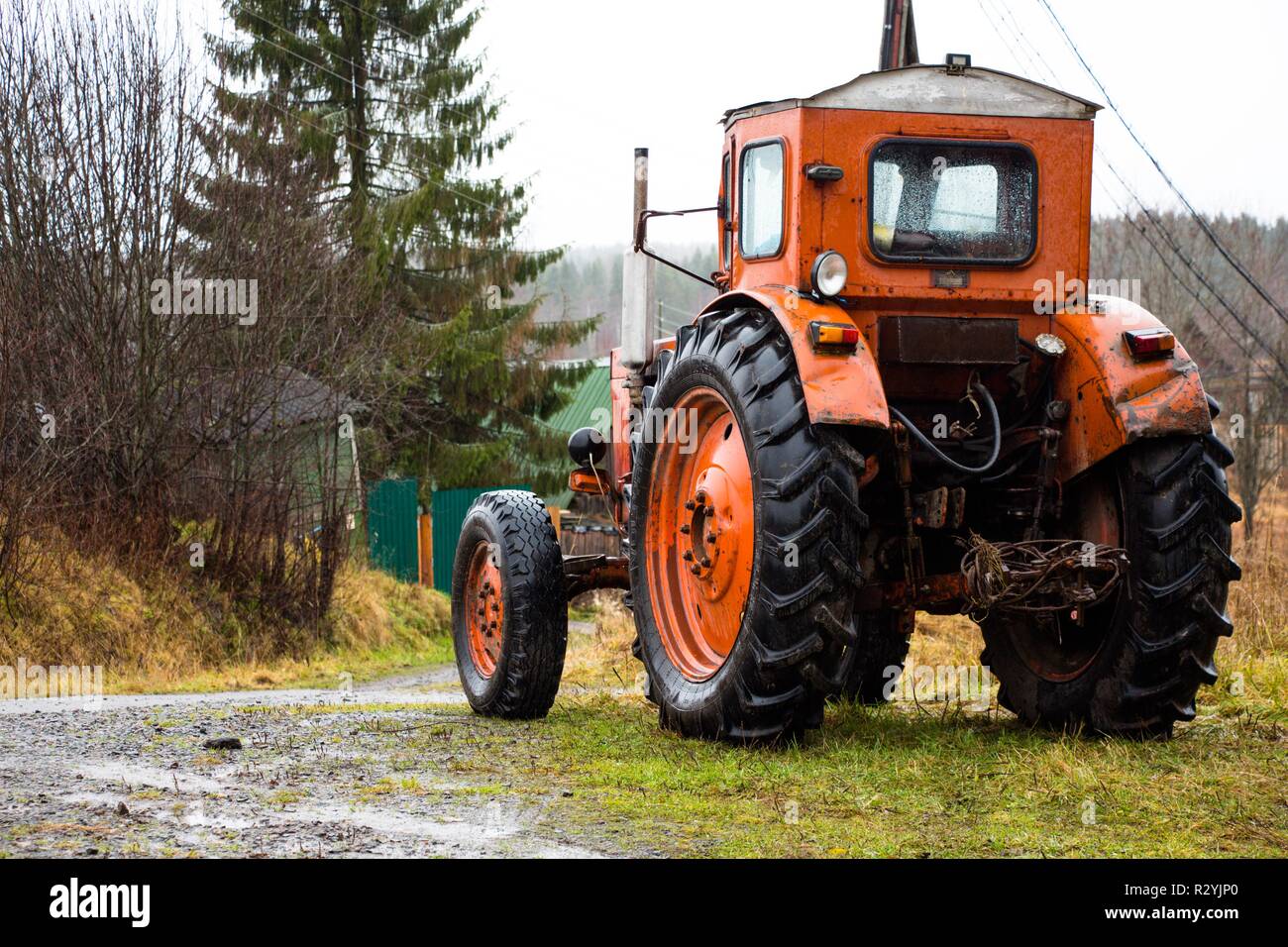Un trattore rosso con grandi ruote sorge su una montagna in campagna. Il trattore è pronto per il lavoro sul campo ed in azienda. Foto Stock