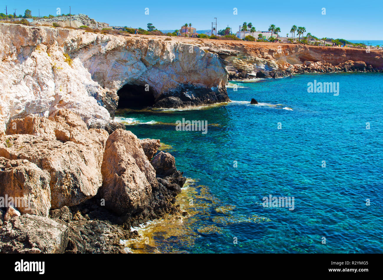 Vista in una grotta nei pressi di Agia Napa, Cipro, maestoso monumento naturale. Giallo bruno alte scogliere di pietra vicino trasparente blu incredibile acqua. Senza nuvole caldo d Foto Stock