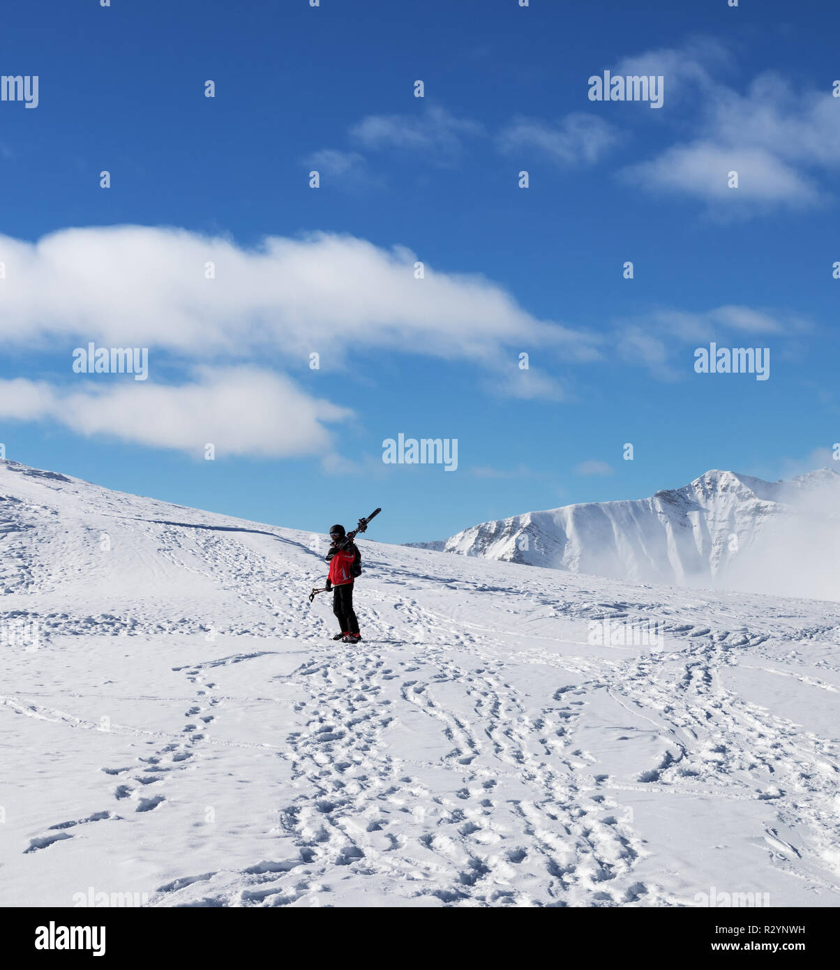 Sciatore con sci sulla sua spalla e montagne innevate a freddo giorno di sun. In inverno le montagne del Caucaso, Georgia, regione Gudauri, Monte Kudebi. Foto Stock