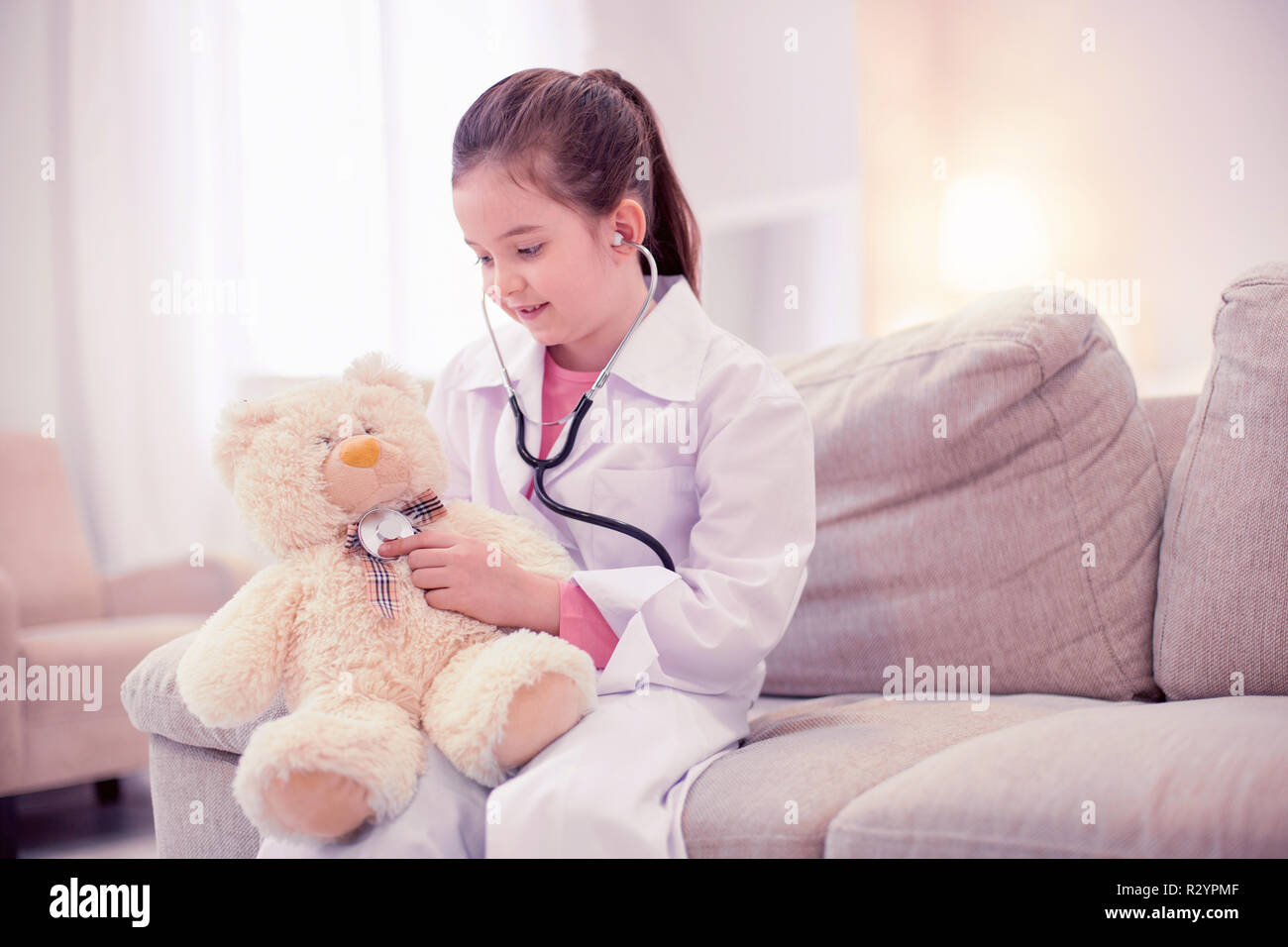 Piccola ragazza in età prescolare indossando giacca bianca a giocare in giochi di medico Foto Stock