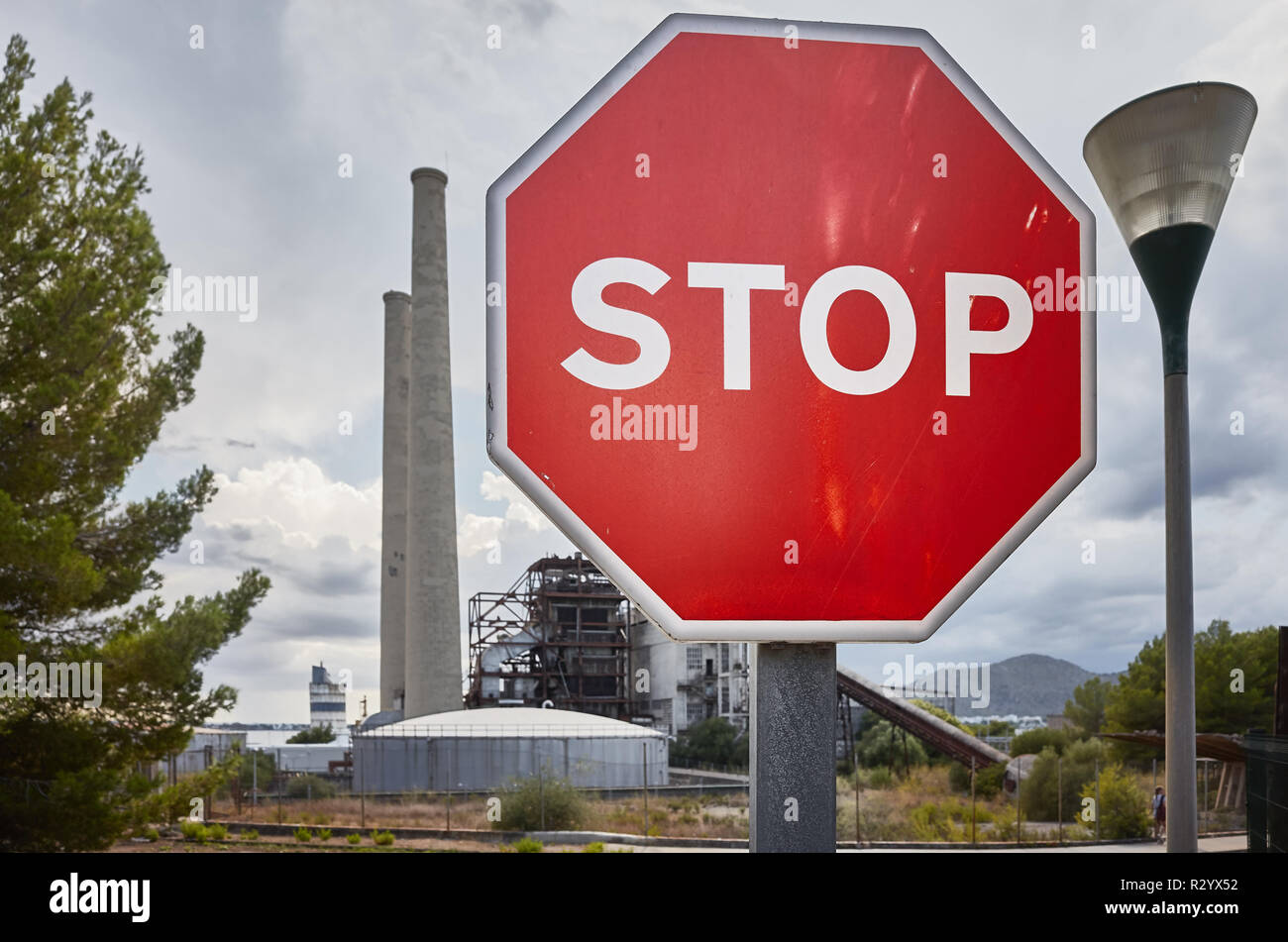 Il segnale di arresto con una fabbrica dietro, inquinamento dell ambiente nozione dell'immagine. Foto Stock