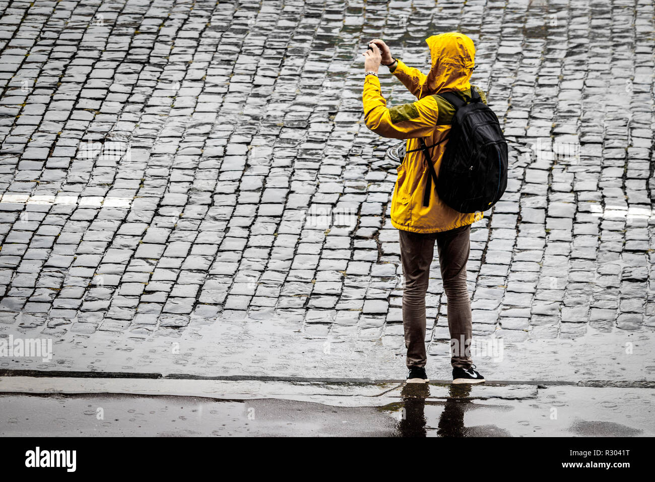 Turista sotto la pioggia sulla Piazza Rossa di Mosca, Russia. Uomo che  indossa il giallo cappotto di pioggia con cappuccio e zaino per fotografare  Foto stock - Alamy