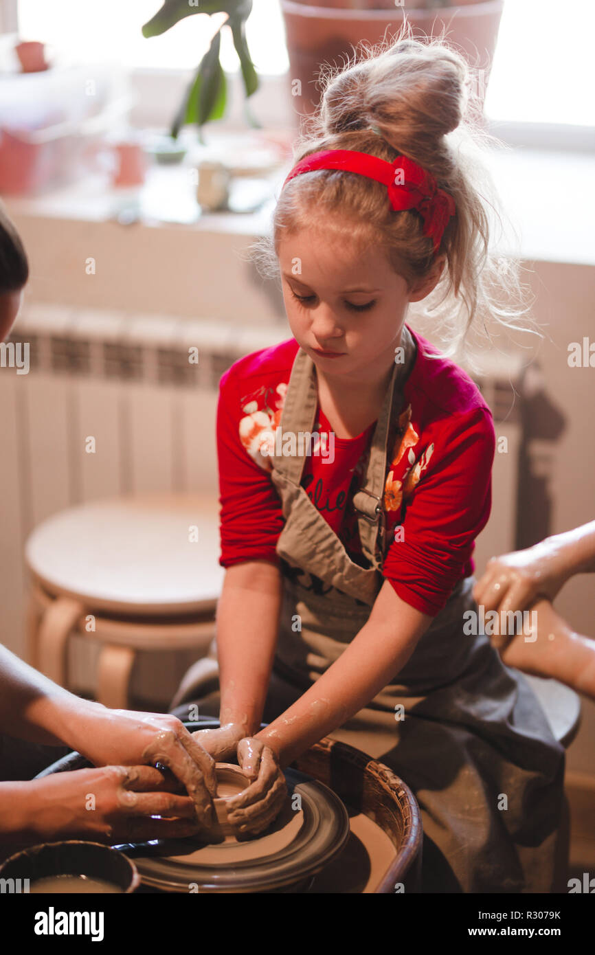 I giovani di sette anni ragazza nel laboratorio di ceramica creando una ciotola da argilla. Laboratorio di ceramica per bambini. Foto Stock