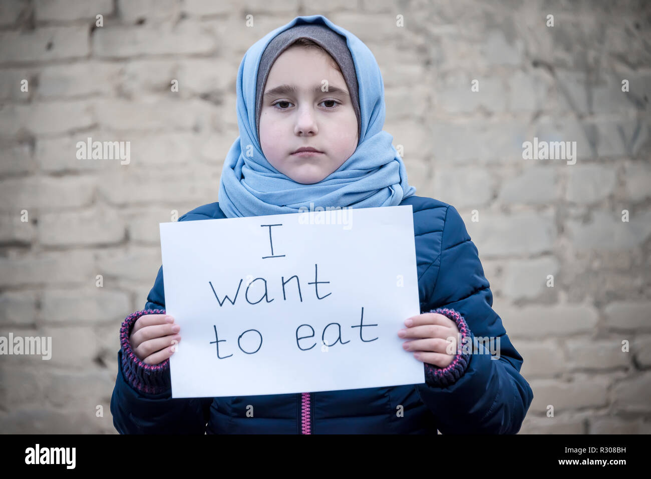 Refugee ragazza con una scritta su un foglio bianco 'voglio mangiare' Foto Stock