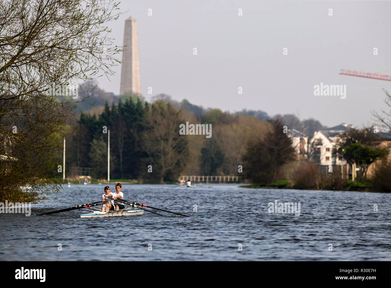 Due giovani uomini canottaggio sul fiume Liffey, con il monumento a Wellington in background Foto Stock