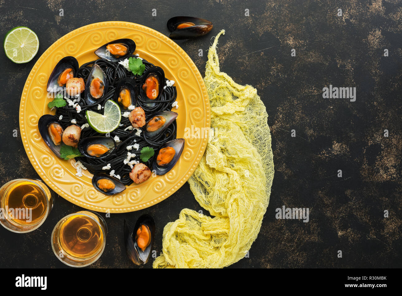 Pasta nera gli spaghetti con le cozze, capesante e vino bianco su uno sfondo rustico. Cucina mediterranea. Vista superiore, spazio di copia Foto Stock