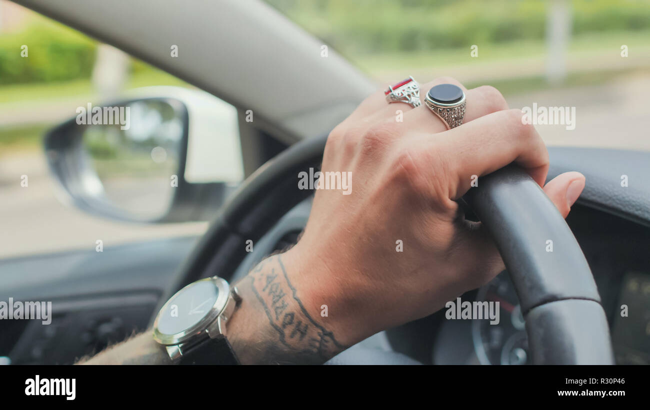 Un uomo con anelli sulla sua mano aziona un'auto. Canto close-up. Foto Stock Un uomo con anelli sulla sua mano aziona un'auto. Canto close-up. Foto Stock