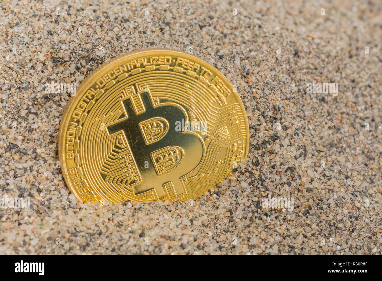 Immagine concettuale di un Bitcoin d'oro affondato nella sabbia - per il crollo del prezzo di Bitcoin 2021, crollo del bitcoin, crollo del mercato della criptovaluta. Foto Stock