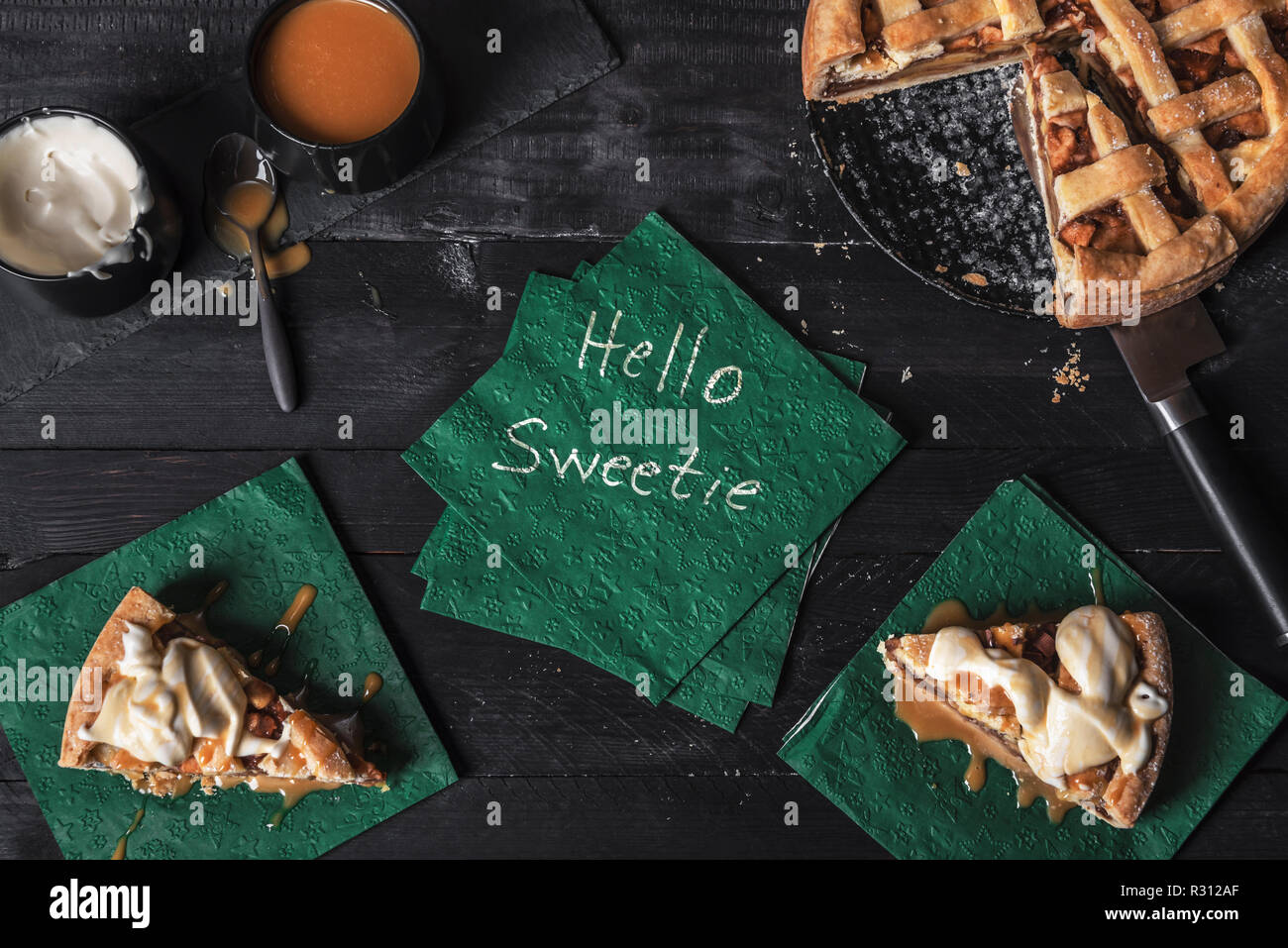 La torta di mele e fette con panna e Topping Caramel e un tovagliolo con le parole ciao sweetie, su un tavolo. Sweetie pie contesto. Dolce tradizionale. Foto Stock