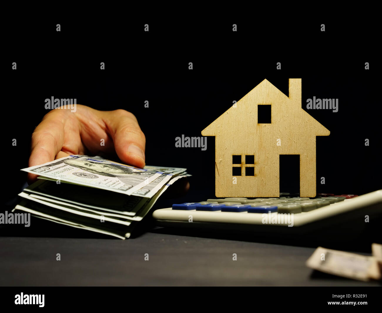 Modello di casa e la mano con il denaro. Prestito di affari per immobili o ipoteca. Foto Stock