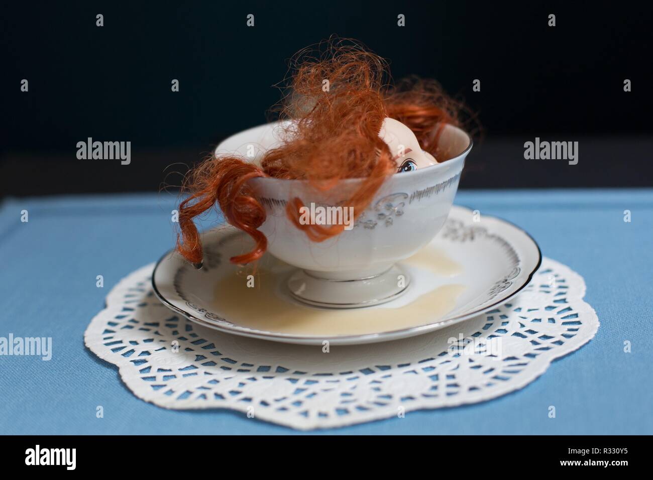 Immagine surreale di red-headed doll in una tazza di tè. Foto Stock