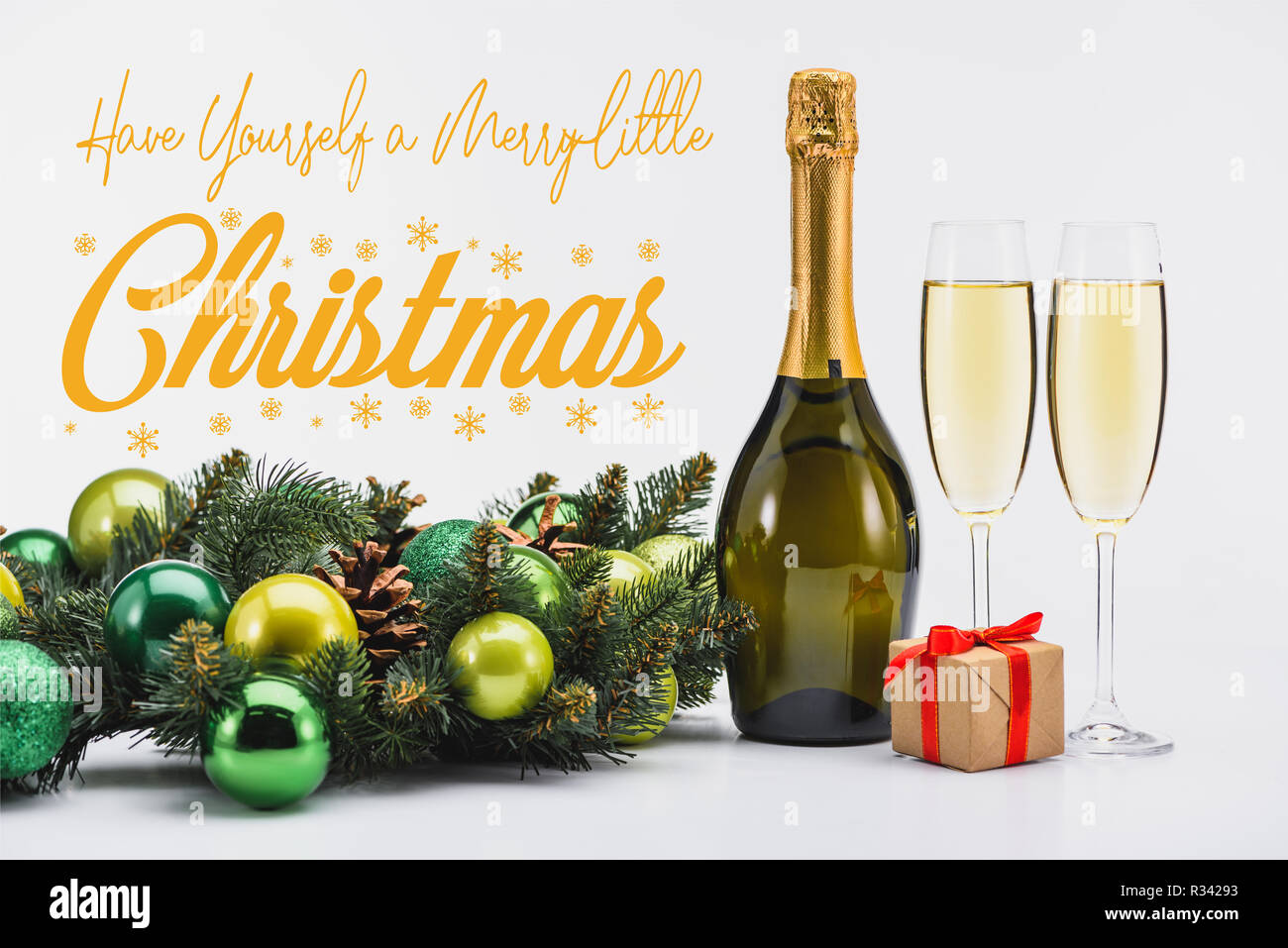 Bottiglia e bicchieri di champagne, ghirlanda di Natale e regalo su sfondo bianco con 'Have Yourself A Merry Little Christmas' ispirazione Foto Stock