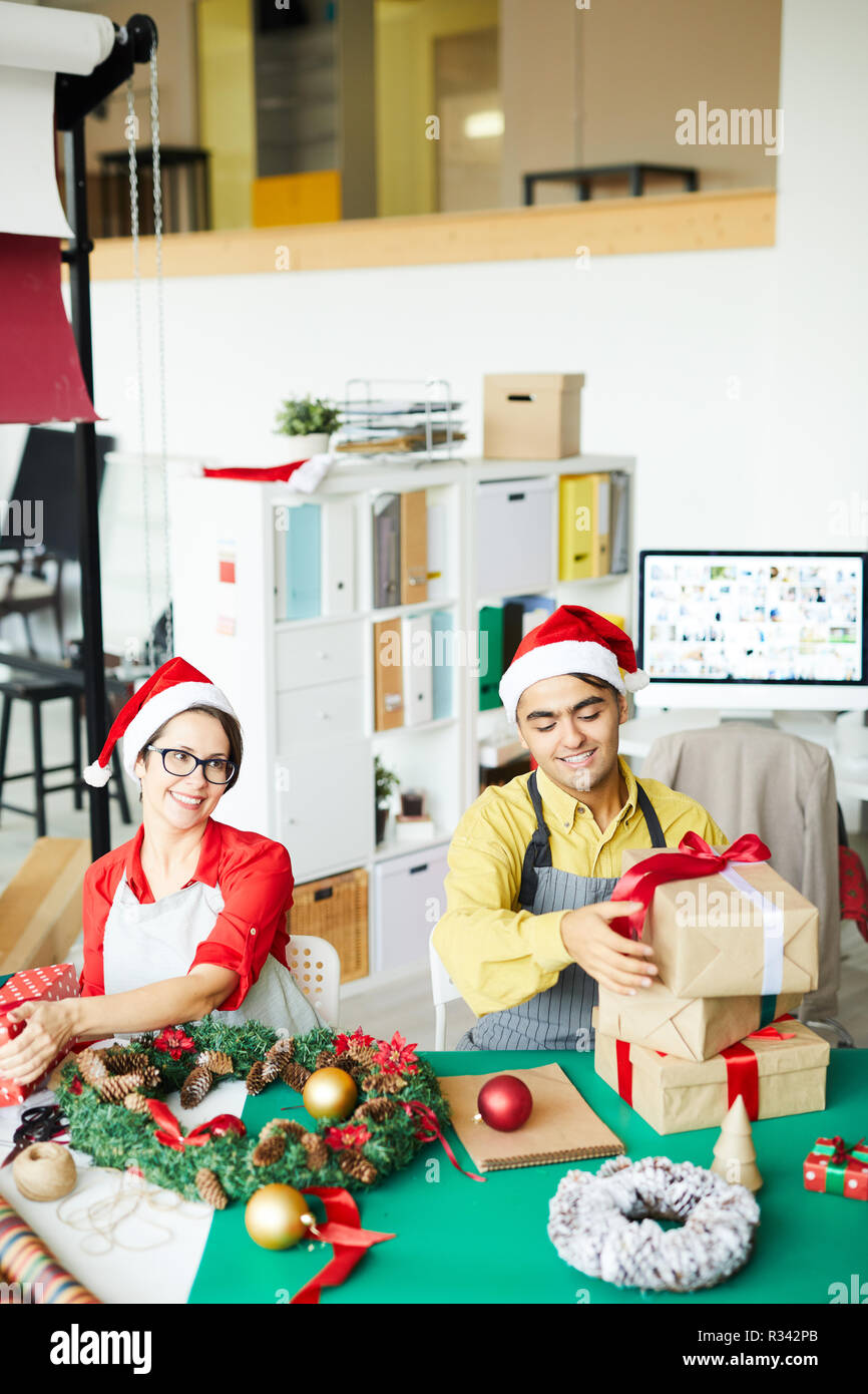 I progettisti di felice in Santa caps la preparazione di regali per Natale e rendendo le decorazioni Foto Stock