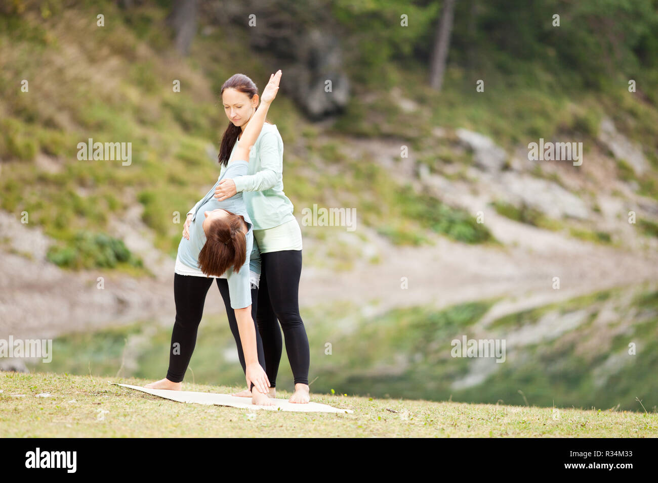 La donna le pratiche yoga con la guida anteriore di un lago Foto Stock