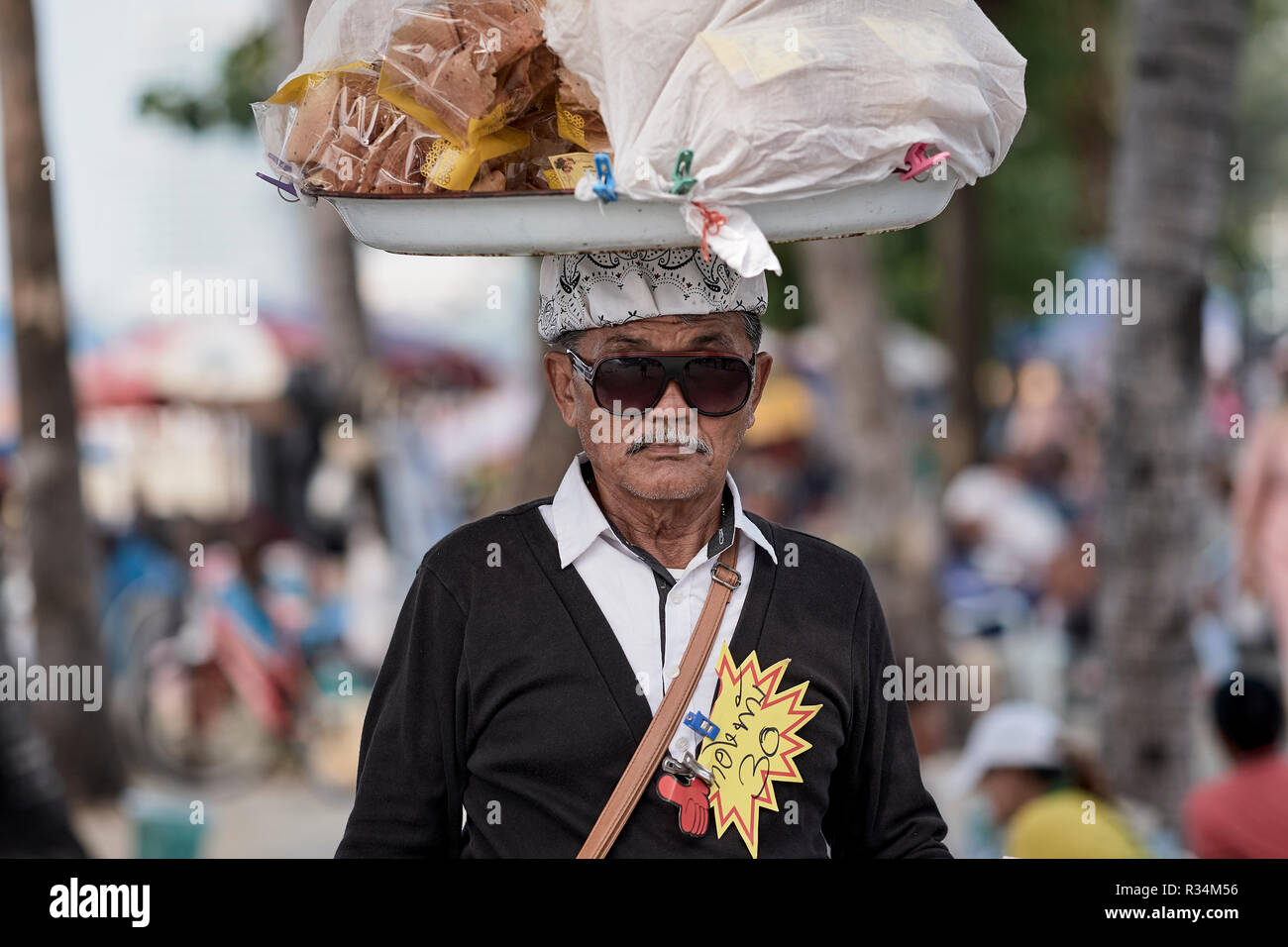 Thailandia venditore di cibo di strada che porta i suoi articoli sulla sua testa Foto Stock