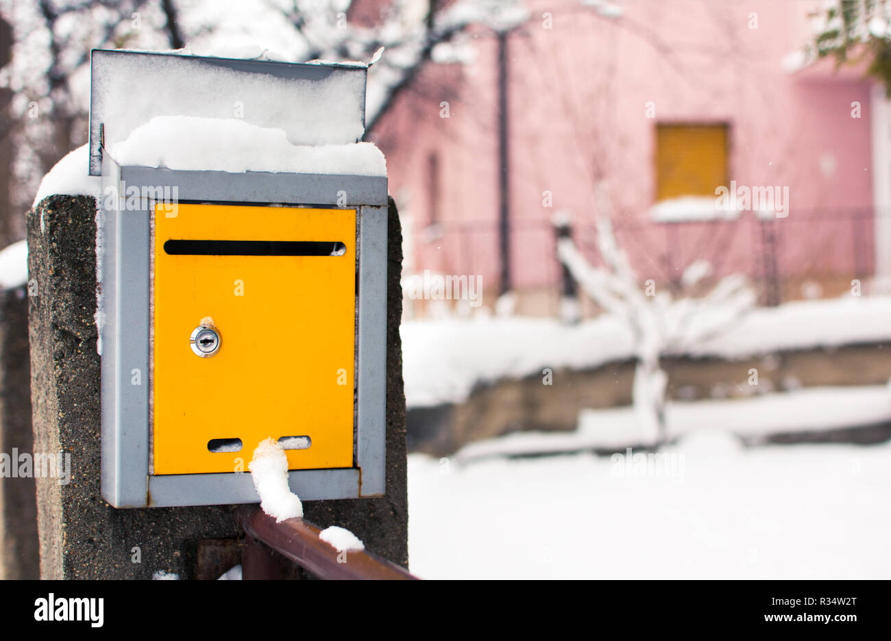 Coperta di neve giallo nella cassetta postale di fronte a una casa Foto Stock