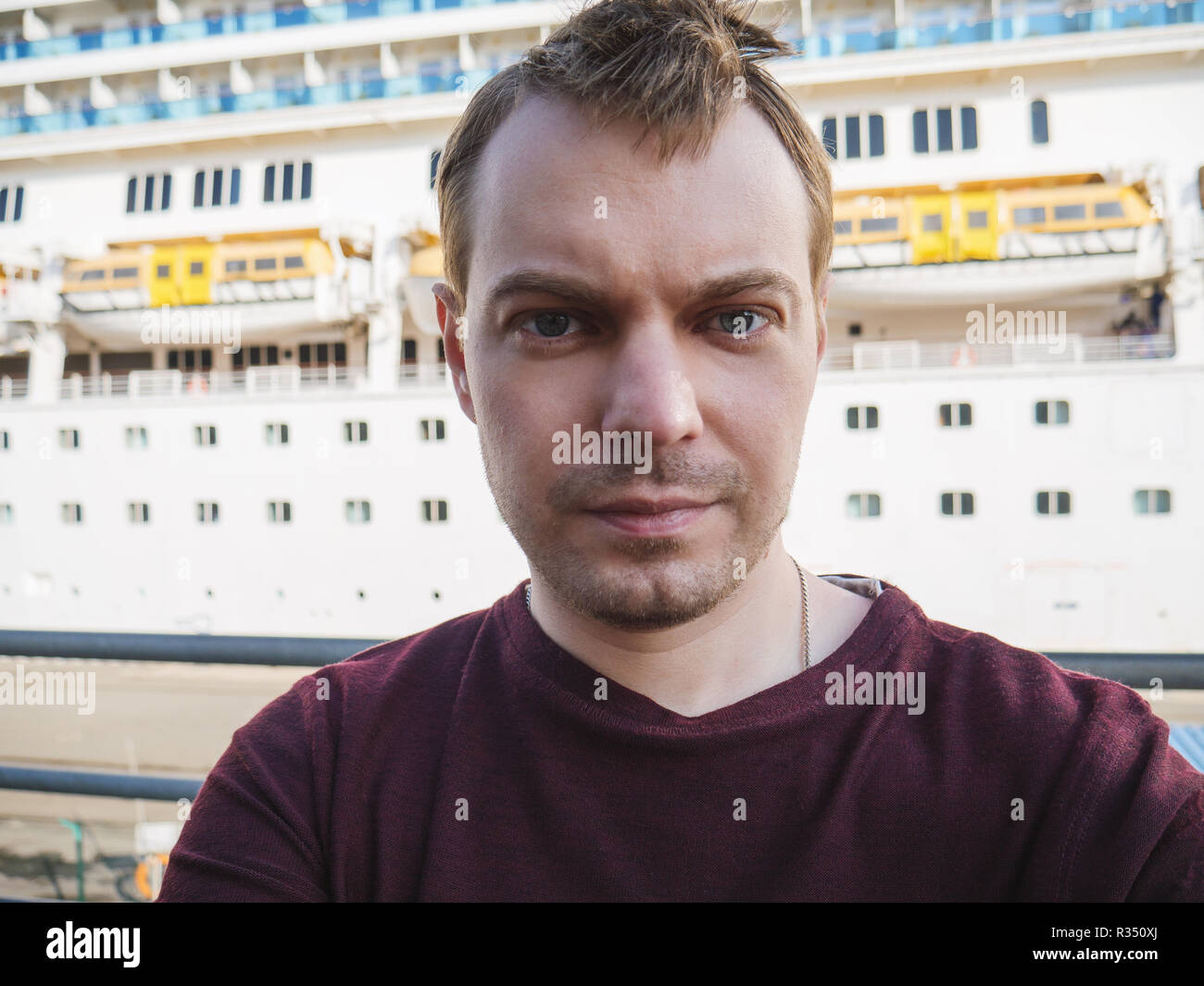 Giovane fa selfie vicino a una nave da crociera. Foto Stock