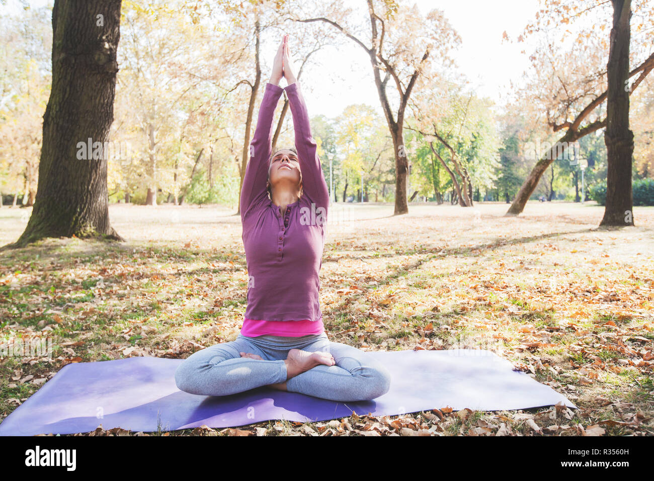 La donna la meditazione e la pratica dello yoga, Lotus pongono, Padmasana. La meditazione sulla soleggiata giornata autunnale al parco. Allenamento all'aperto. Foto Stock