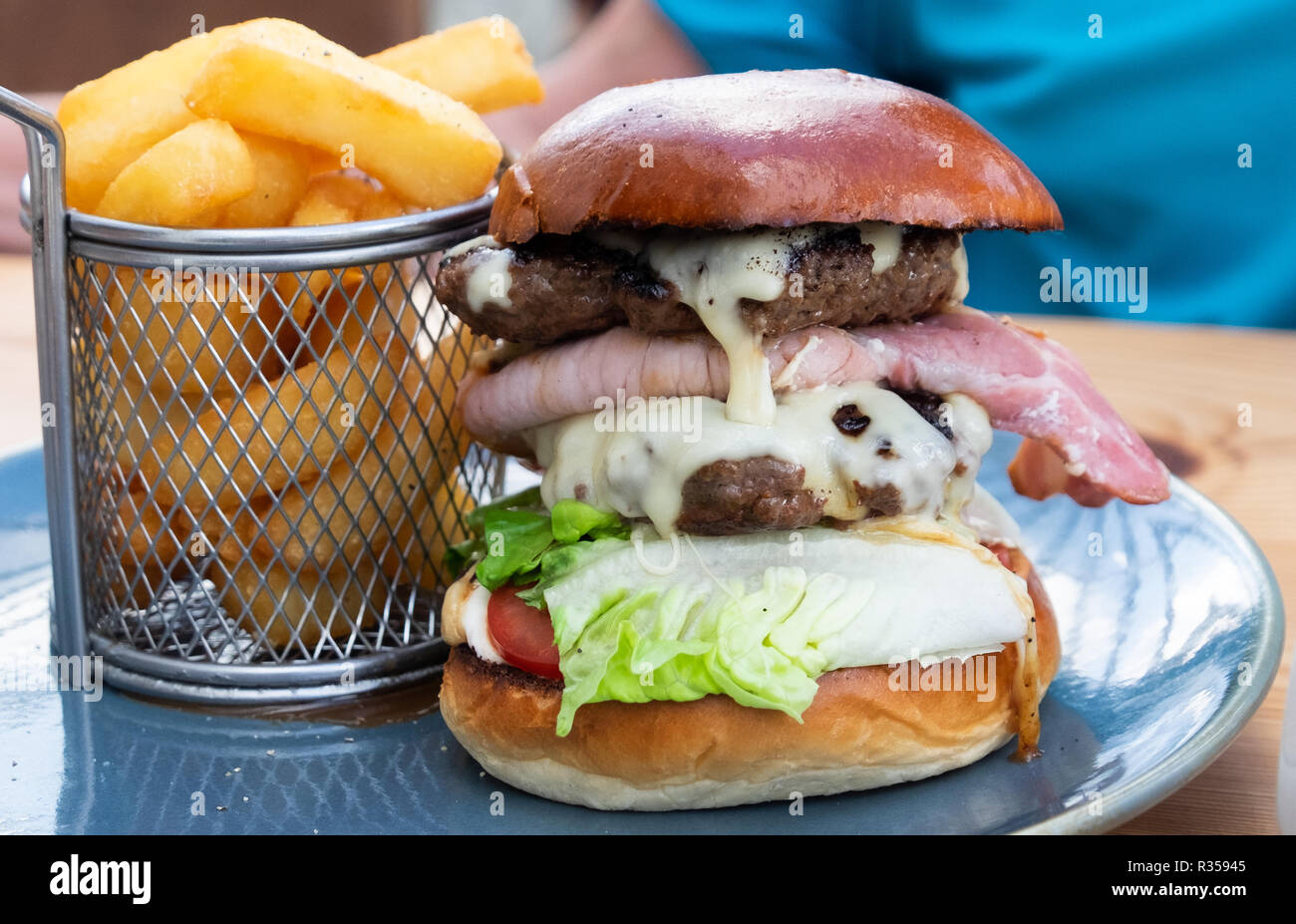 Grande caldo e delizioso double cheeseburger pila di bun con insalata e salsa condito con chip in corrispondenza di naufraghi, ristorante, Mylor, Cornwall. Foto Stock