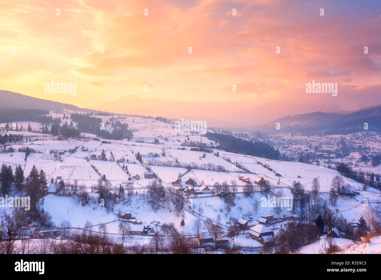 Incantevole paesaggio invernale in morbida luce del tramonto, valle alpina circondata da montagne ricche di boschi, nei Carpazi Foto Stock