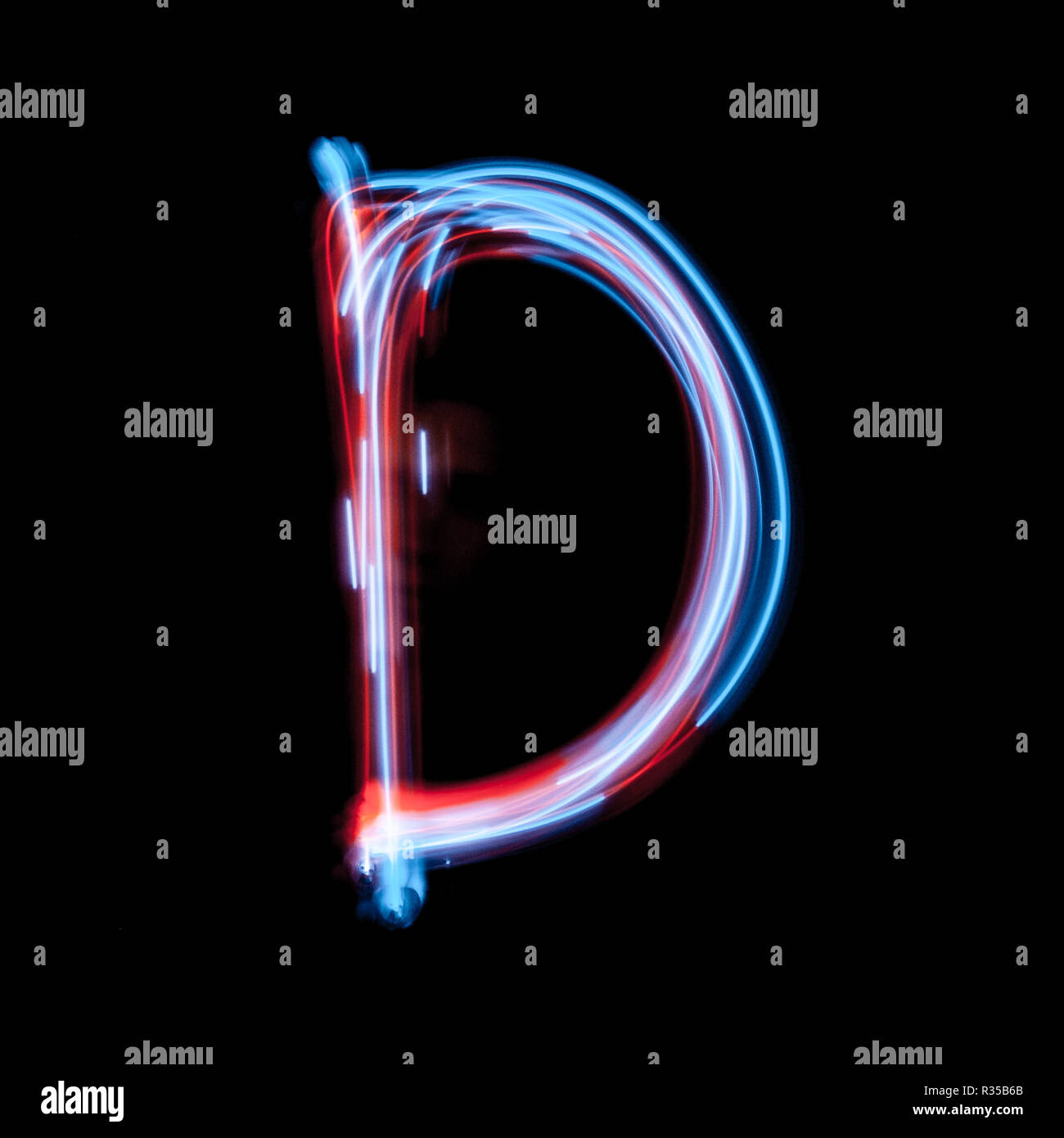 Lettera D dell'alfabeto realizzato dal segno al neon. La luce blu immagine, esposizione a lungo con colorate luci fairy, contro uno sfondo nero Foto Stock