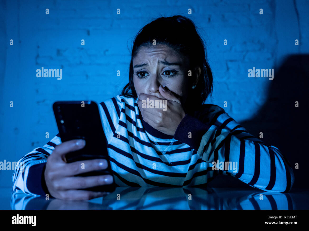 Frightened adolescente o giovane donna utilizzando smart telefono cellulare come internet cyberbullismo dal messaggio sgambate abusato della vittima. Foto Stock