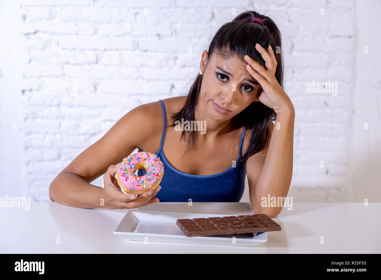 Fame bella giovane donna infelice craving dolce al cioccolato e ciambelle e non possono mangiare nella dieta di perdita di peso di zucchero diabetici di tossicodipendenza e unhealth Foto Stock