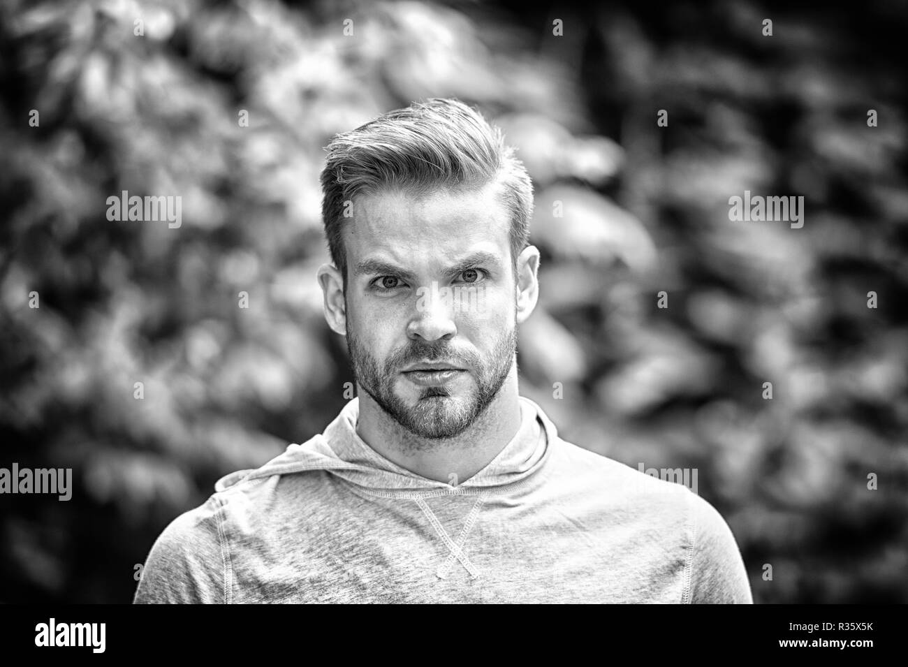 Bello stile. Guy barbuto attraente si preoccupa di aspetto. Uomo di setole faccia gravi, natura verde, sfondo sfocato. Concetto Metrosexual. Uomo barba lunga barba guy sembra bello e fresco. Foto Stock