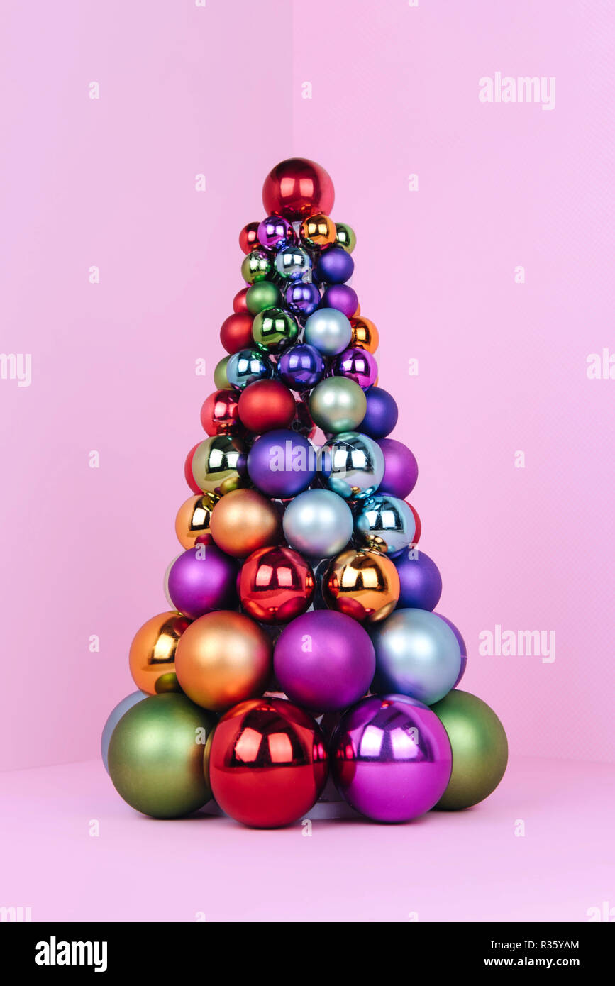 Albero di Natale fatto di decorazione a sfera su sfondo rosa. Foto Stock