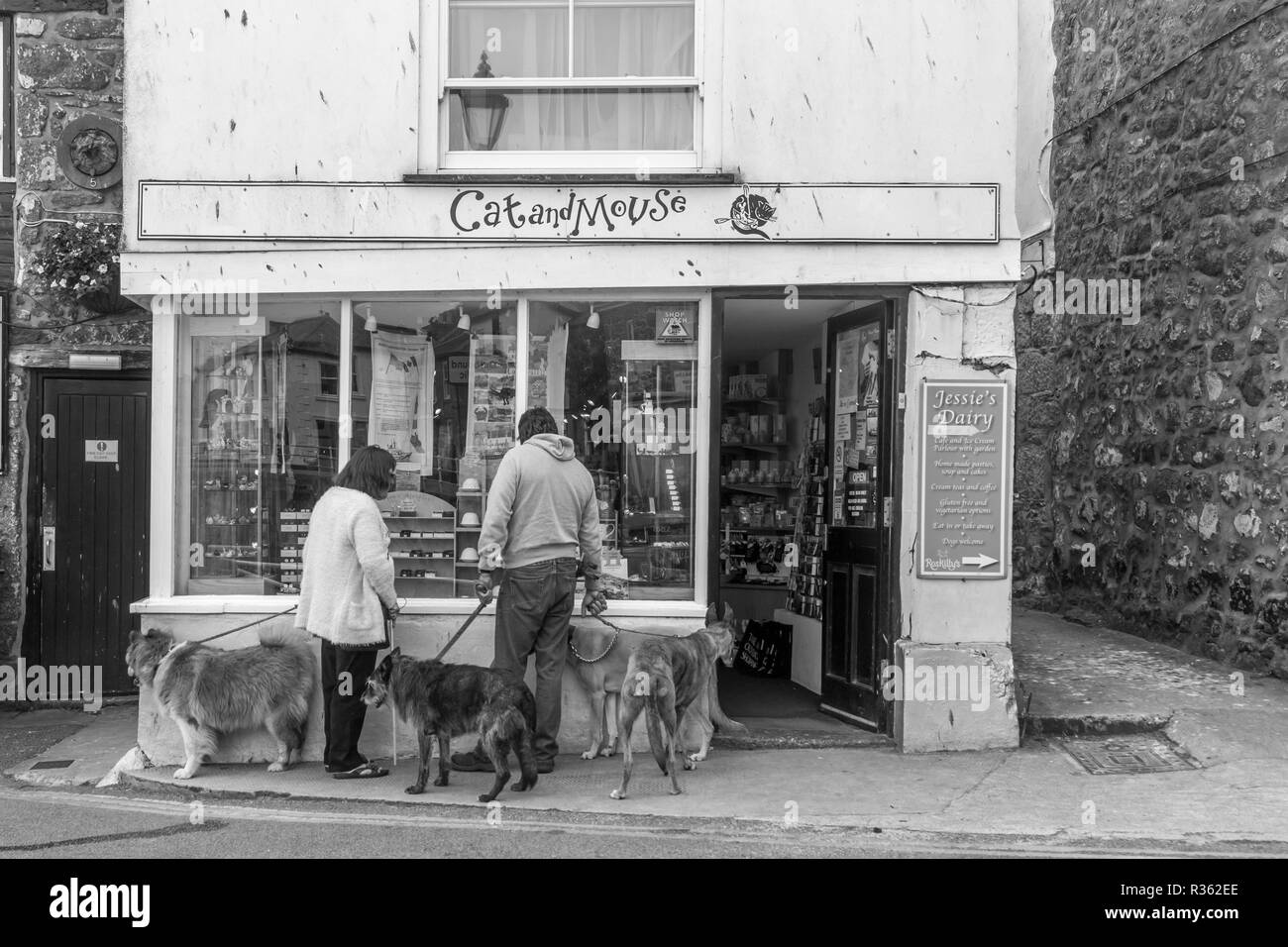 Un giovane al di fuori di un negozio locale nel villaggio costiero di Mousehole in Cornovaglia Foto Stock