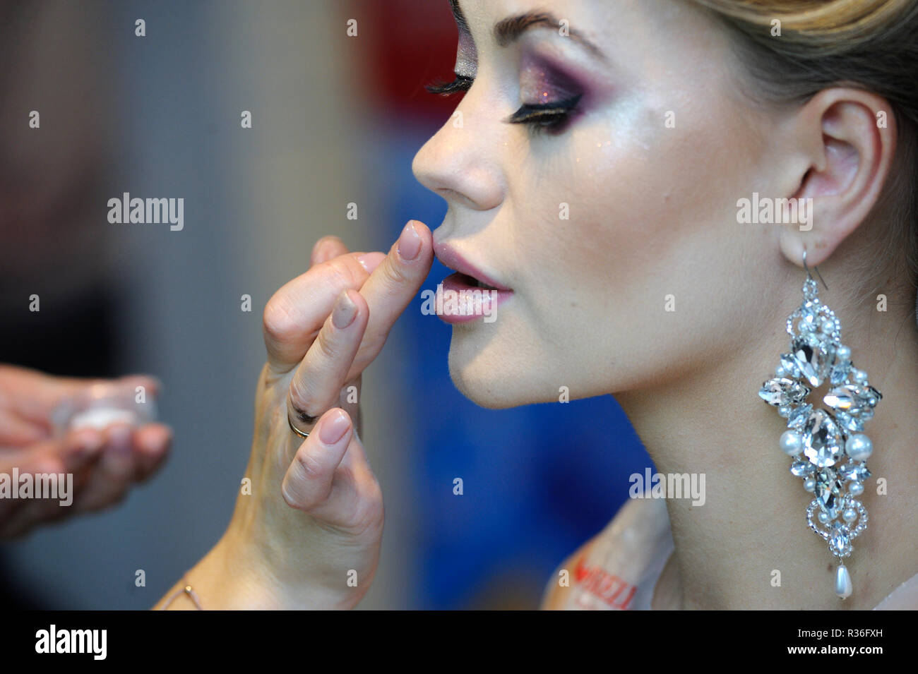 In un salone di bellezza. Make-up artist dito del labbro di fissaggio di lucentezza in una femmina del cliente le labbra. Kiev, Ucraina. Novembre 8, 2018 Foto Stock