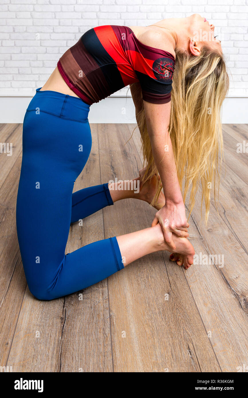 Donna con capelli lunghi biondi facendo esercizi yoga Foto Stock