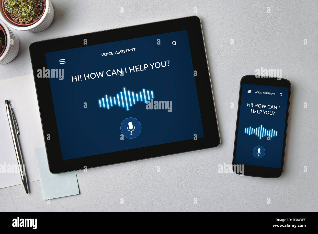 Assistente vocale concetto su tablet e lo schermo dello smartphone su tabella grigia. Tutti i contenuti della schermata è progettato da me. Lay piatto Foto Stock