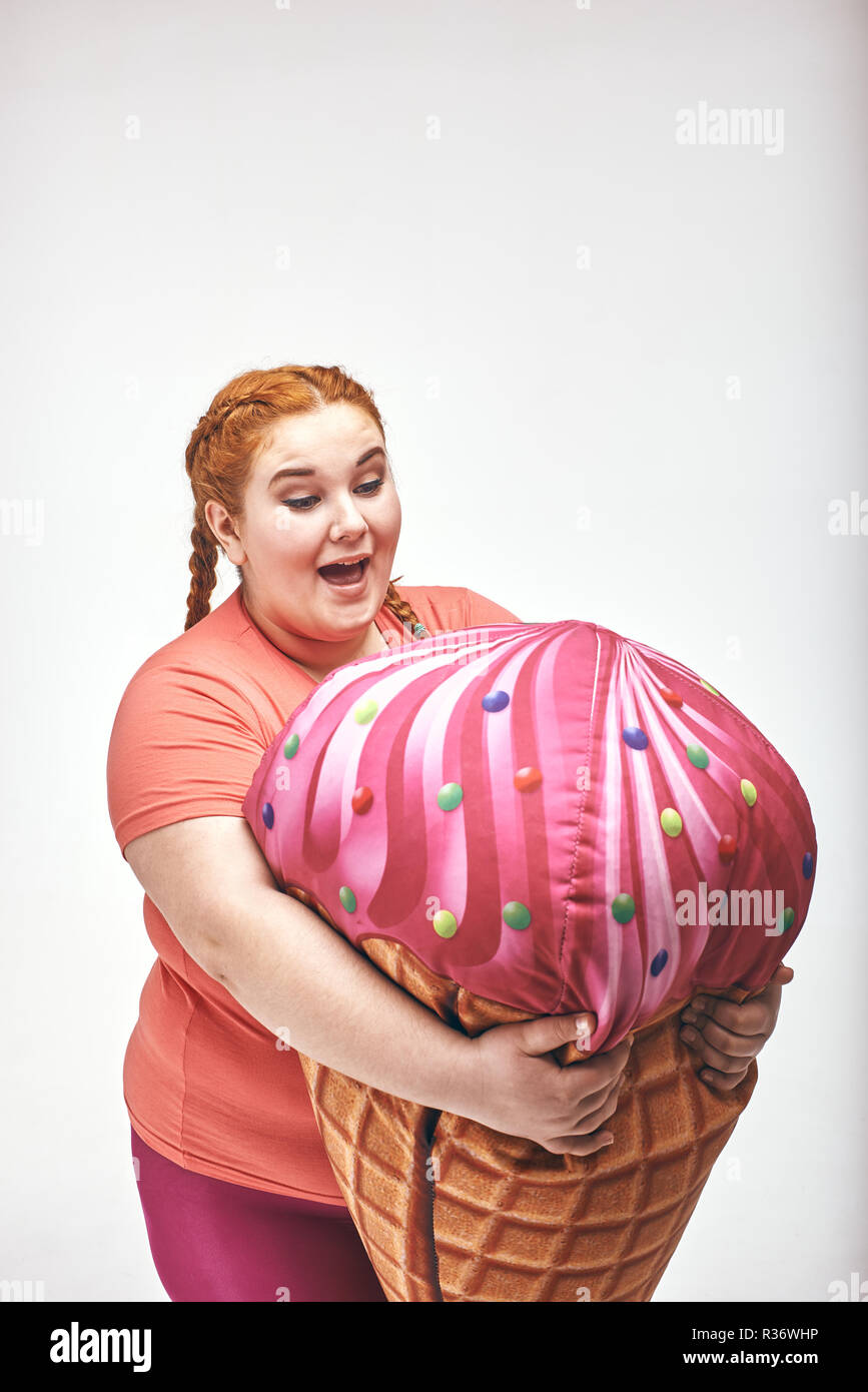 Dai capelli rossi, chubby donna è in possesso di un enorme gelato Foto Stock