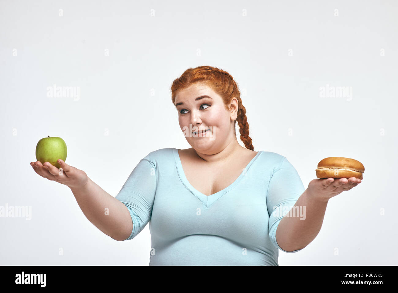 Dai capelli rossi, chubby donna è scelta tra apple e sandwich Foto Stock