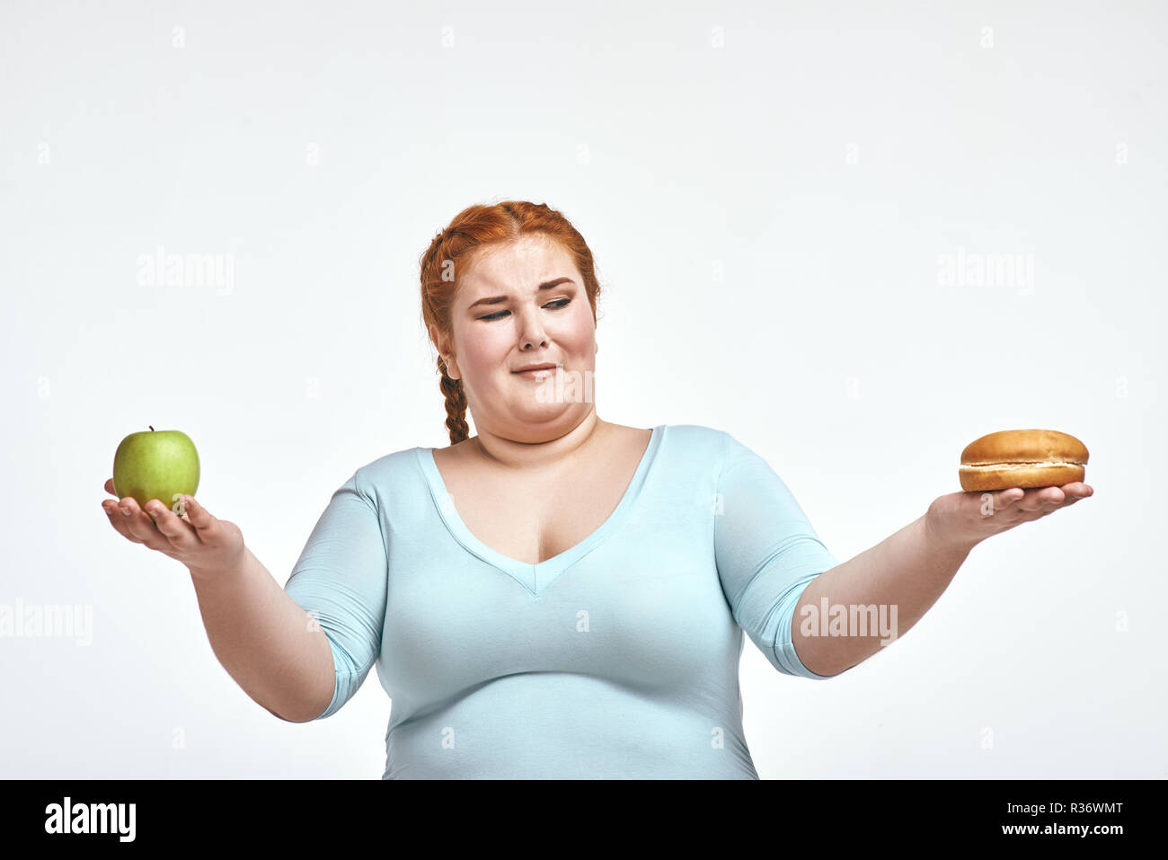 Dai capelli rossi, chubby donna è scelta tra apple e sandwich Foto Stock