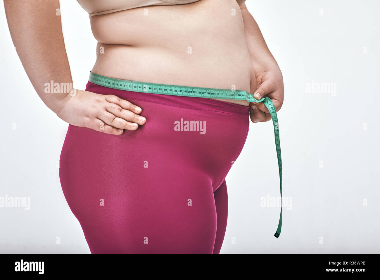 Chubby donna è la misura del suo ventre su sfondo bianco Foto Stock