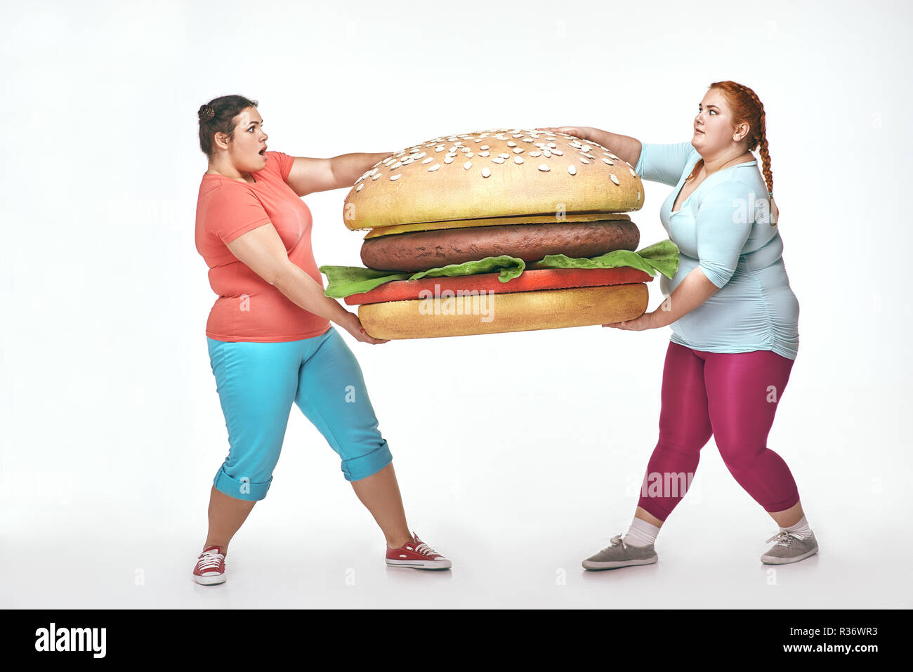 Due chubby le donne sono in possesso di un enorme panino Foto Stock