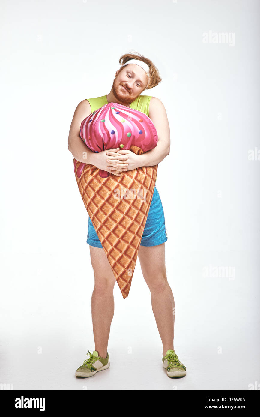 Dai capelli rossi, barbuto, paffuto uomo è in possesso di un grosso gelato Foto Stock