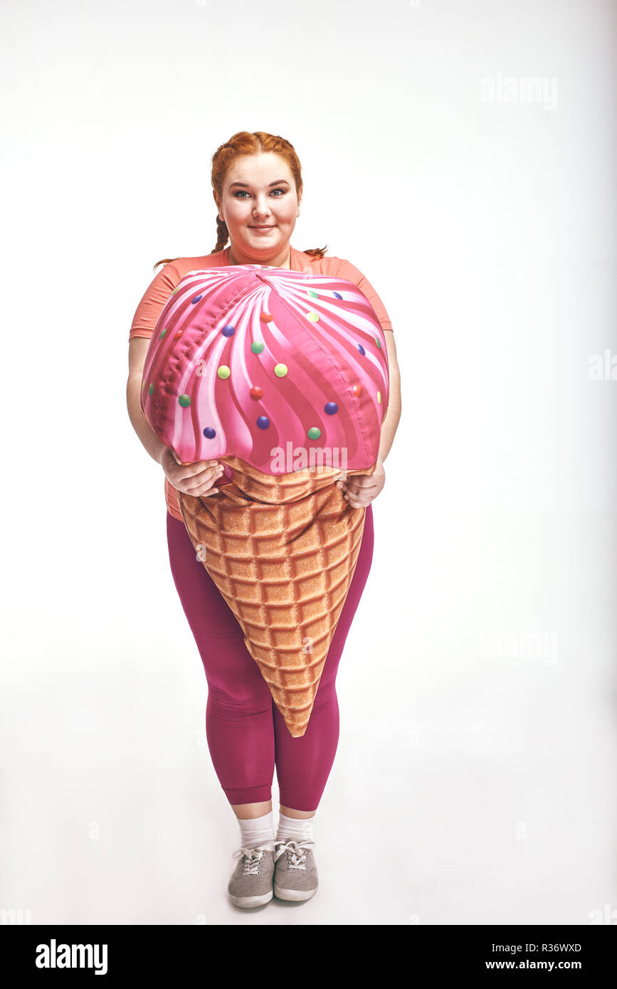 Dai capelli rossi, chubby donna è in possesso di un enorme gelato Foto Stock