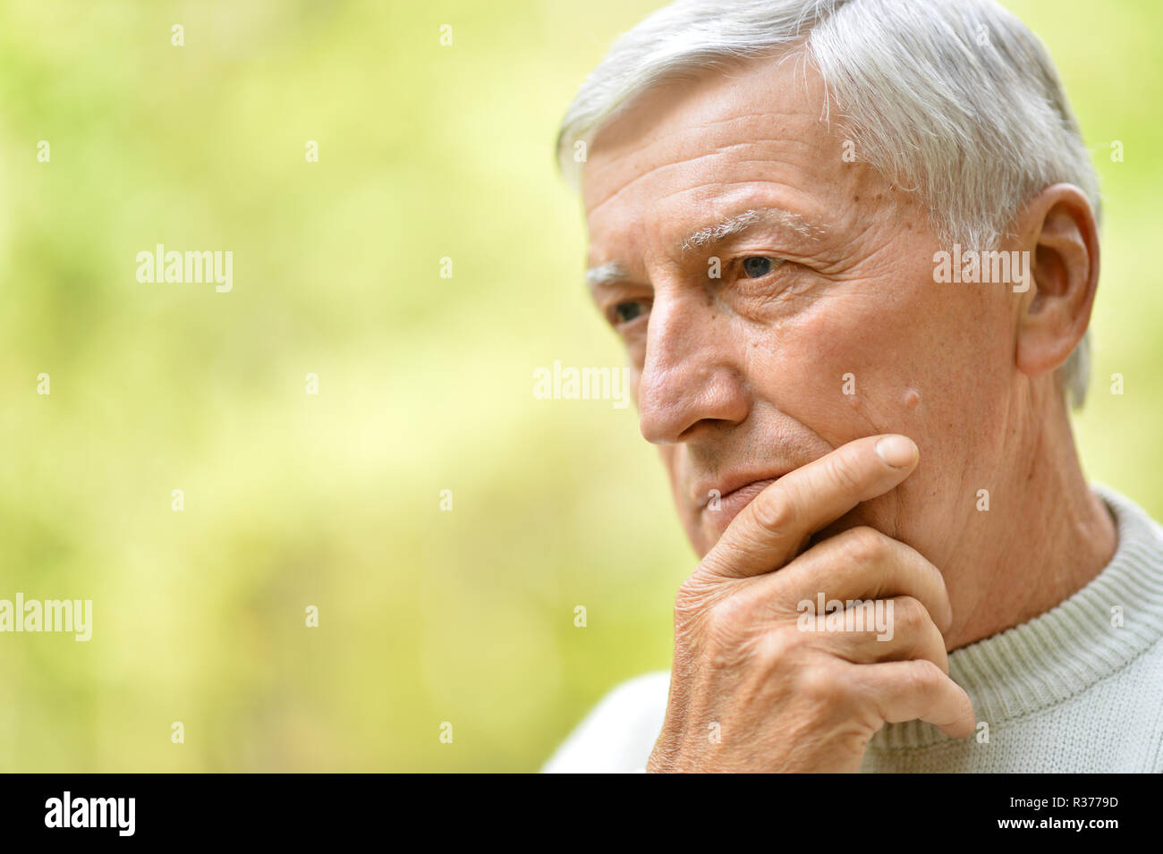 Ritratto di uomo anziano nel parco su sfondo verde Foto Stock