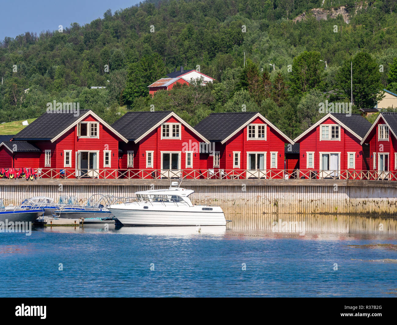 Tipico rosso-bianco in legno case vacanze, pier con barche da diporto, Lyngen,Lenangsstraumen, penisola di Lyngen Foto Stock