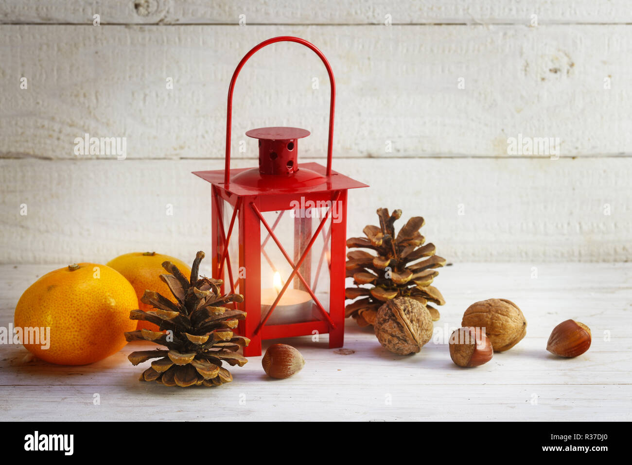 Rosso a lume di candela lanterna, tangerini, coni e dadi, decorazione di Natale sul bianco rustico in legno dipinto, spazio copia selezionata, focus, esigua profondità di f Foto Stock